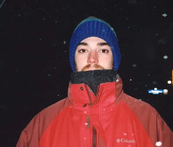 Film photo of Michael at night in falling snow, in a red jacket and blue toque