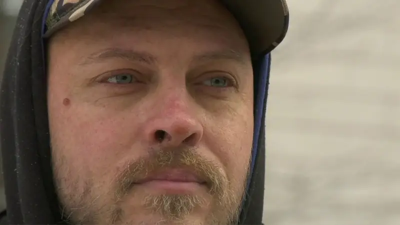 Still from Left in the Cold: close-up of a man in a hood and cap